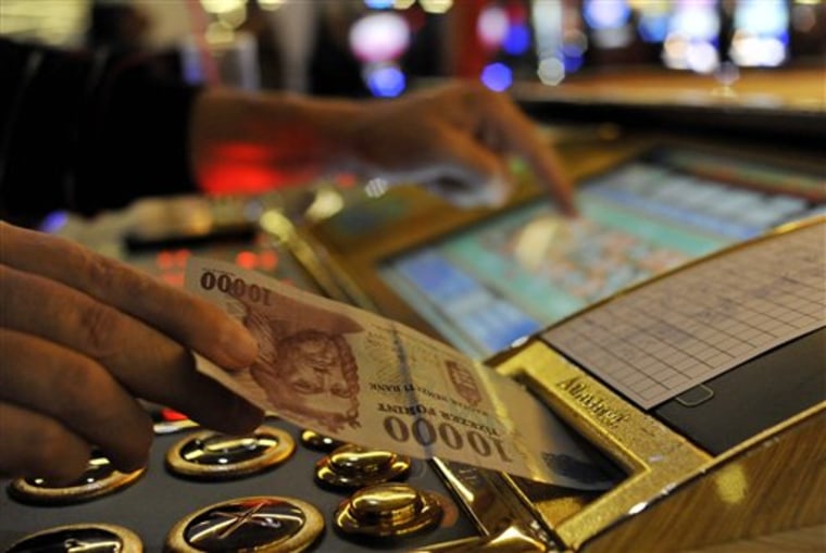 A man inserts a bill into a slot machine roulette in a gambling hall in Budapest, Hungary, Wednesday. 